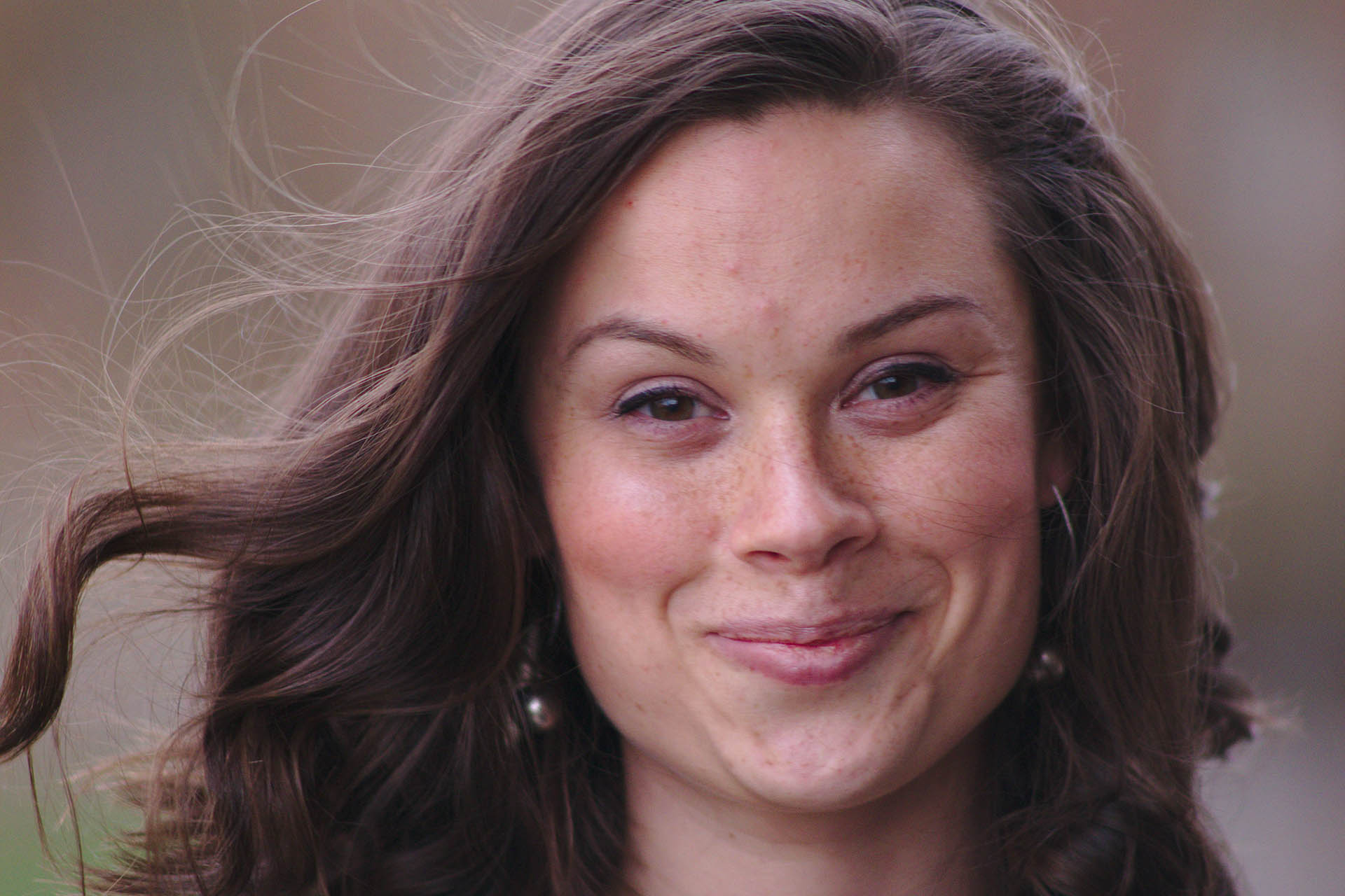 En närbild på en brunhårig tjej med lite fräknar på näsan som ler mot kameran.