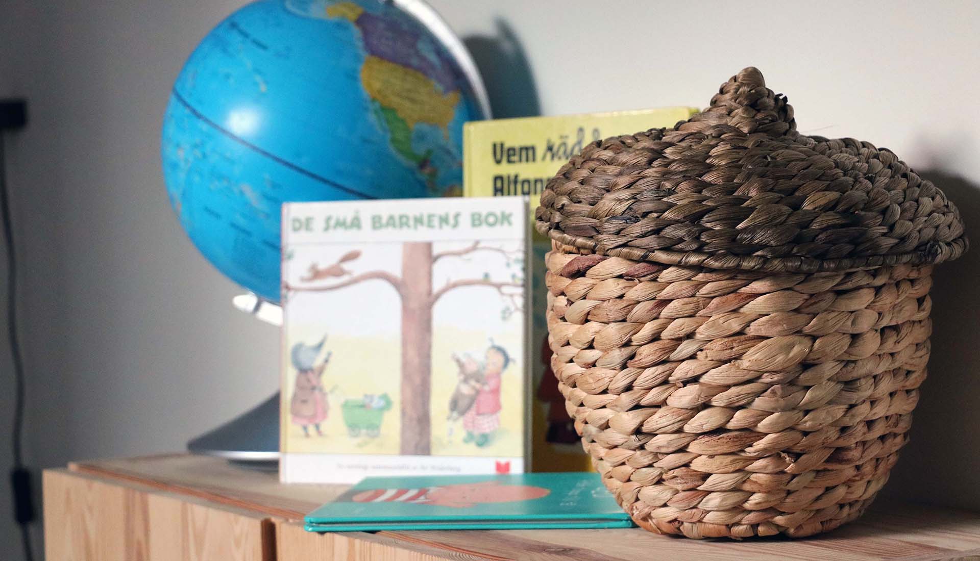 En bokhylla med en korg, jordglob och barnböcker