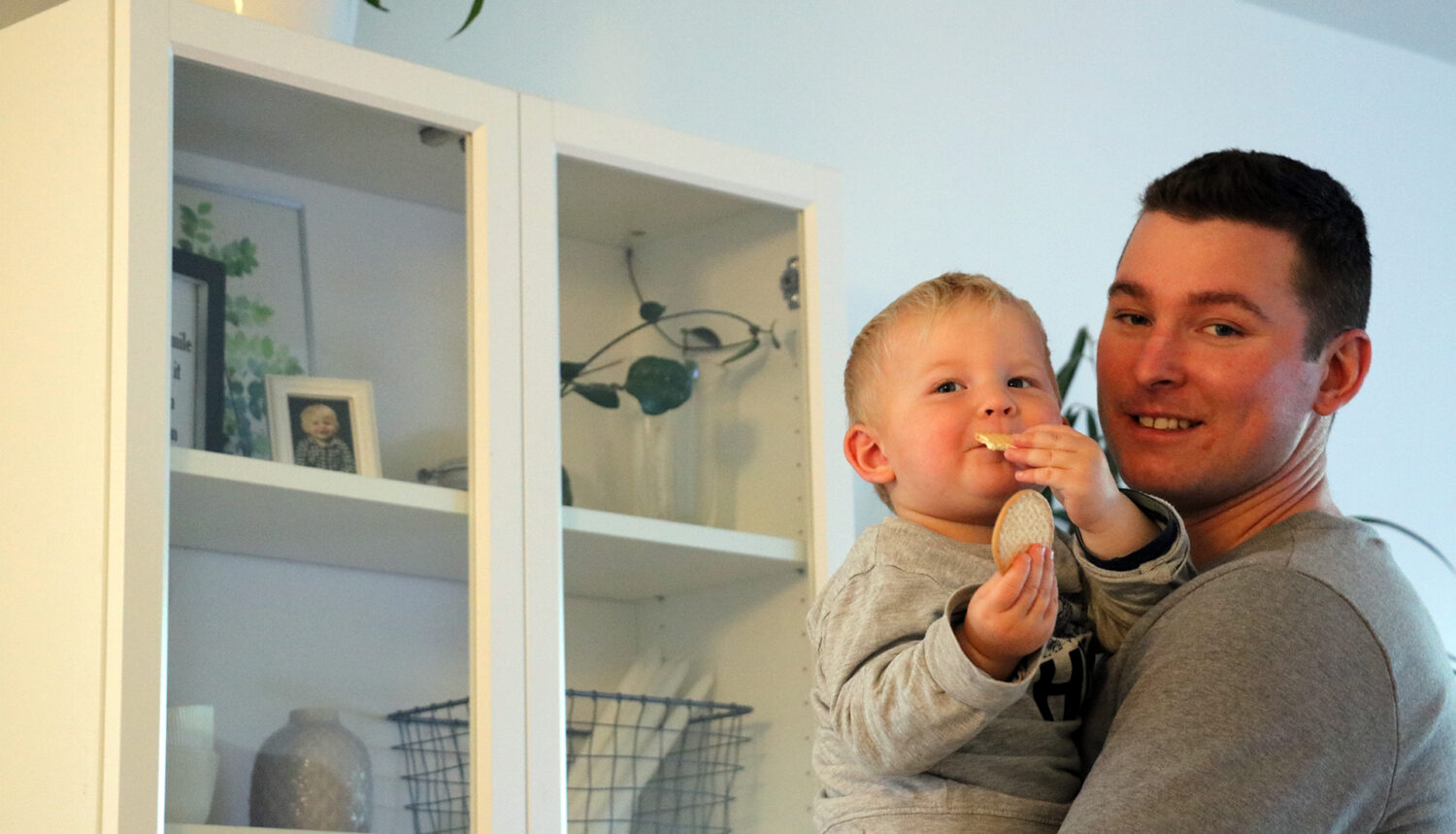 En pappa med sin son står vid ett vitt vitrinskåp