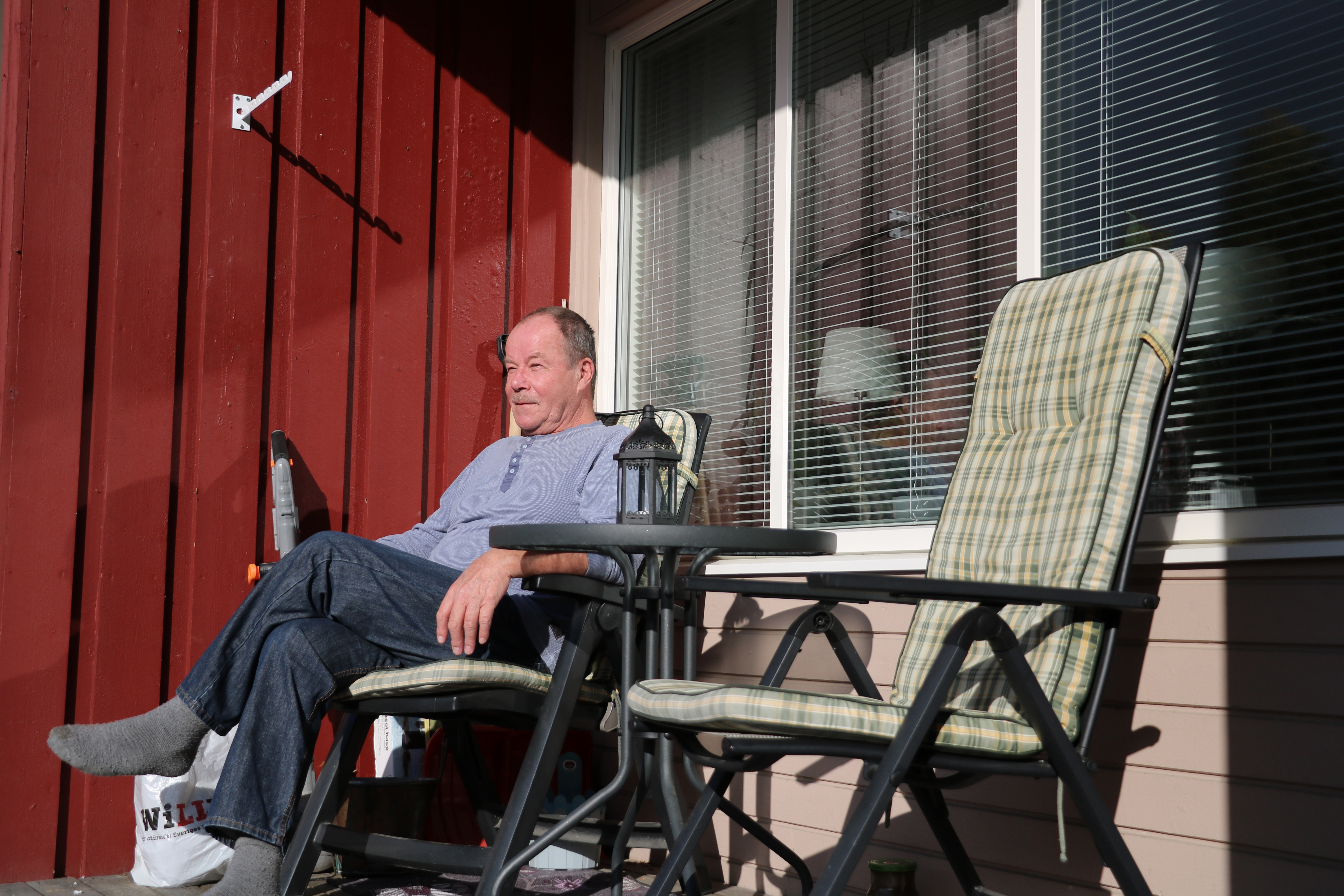 En man sitter ute på altanen i en solstol