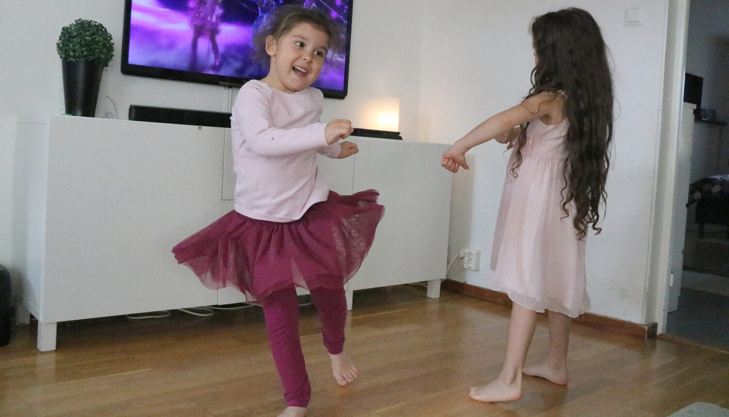 Två små flickor dansar i ett vardagsrum