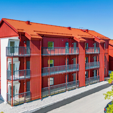 Ett rött bostadshus på tre våningar med balkonger