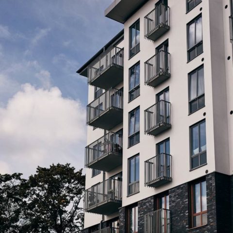 Ett grått och vitt bostadshus med balkonger
