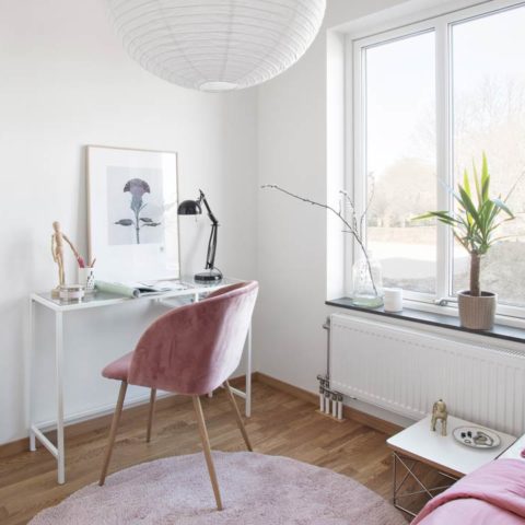 Ett skrivbord och en rosa stol och matta