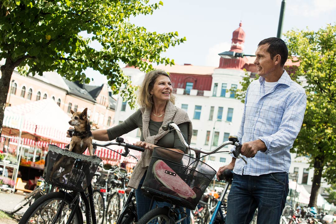 En kvinna och en man går med sina cyklar på ett torg i en stad