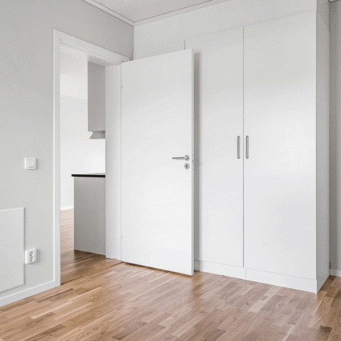 Ett rum med en vit dörr och en vit garderob
