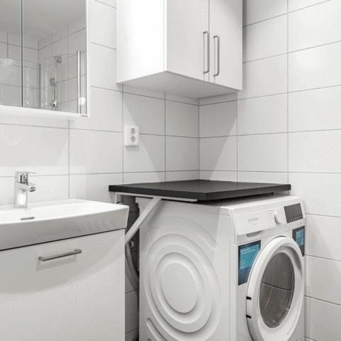 Ett badrum med tvättmaskin och komod