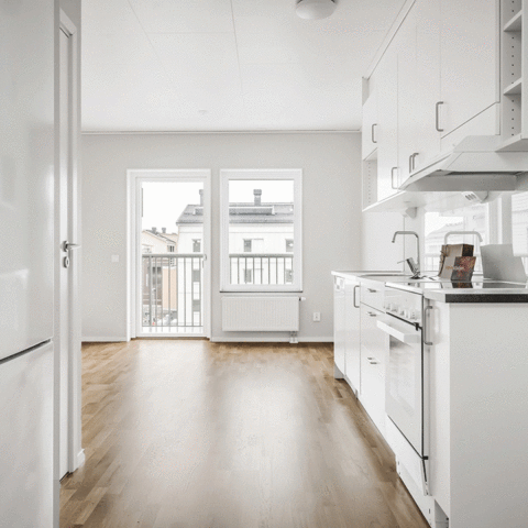 Ett tomt och vitt kök med trägolv