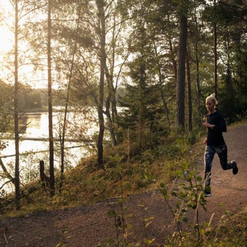En kvinna som springer i en skog på stig.