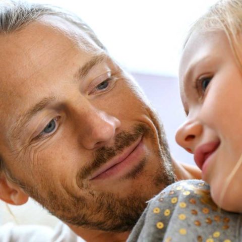 En man och en ung tjej sitter nära varandra och ler mot varandra