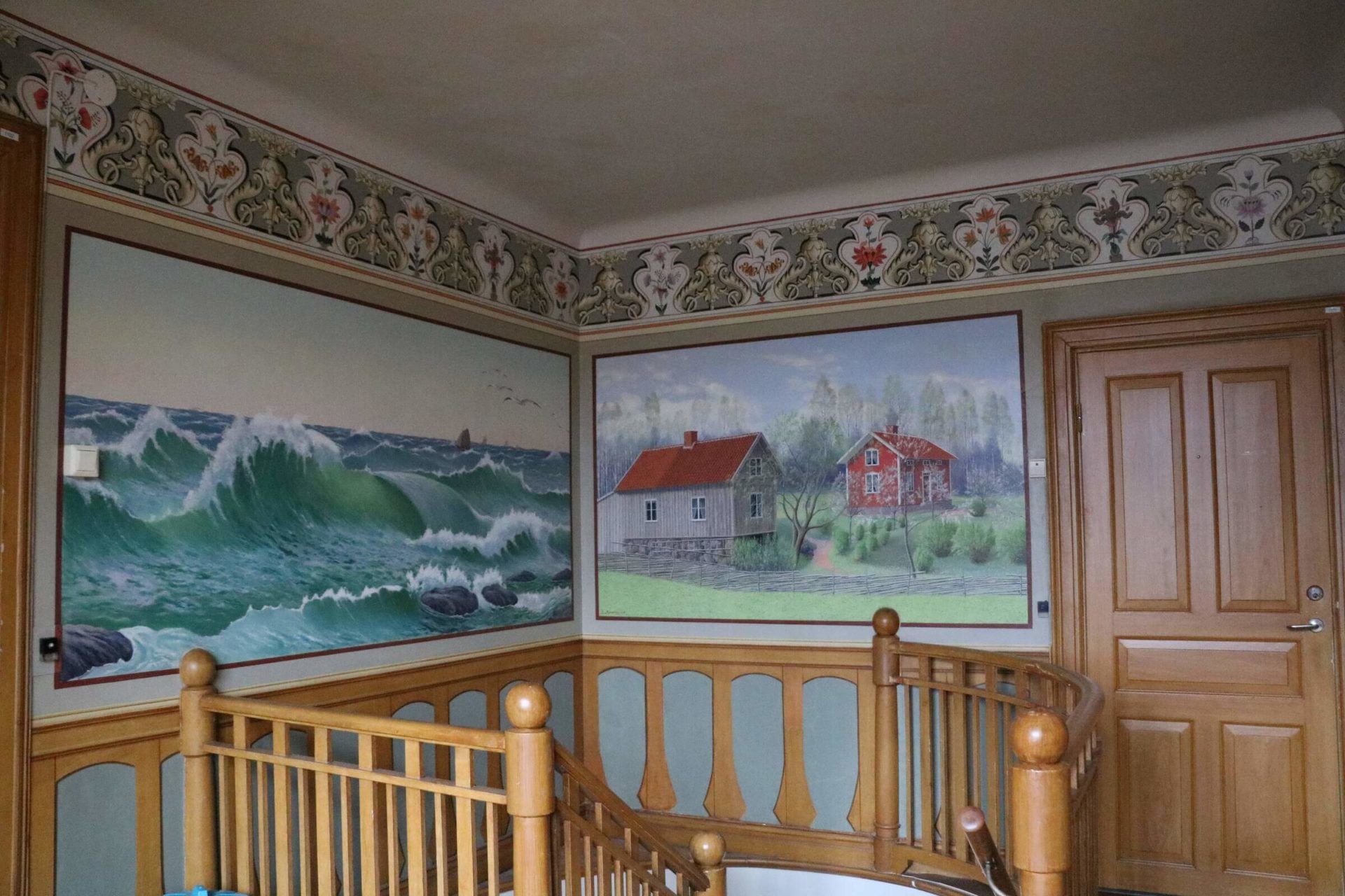 Ett rum med gamla tavlor på väggen och en bård längst upp i taket