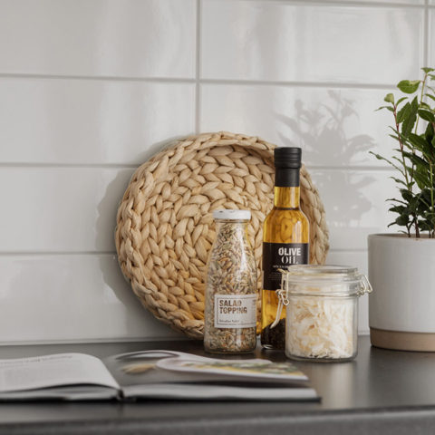 En närbild på ett vitt kakel och en kokbok som ligger öppen på köksbänken