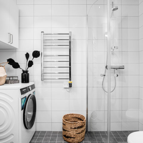 Ett vitt badrum med en badrumstork och en tvättmaskin som står på golvet
