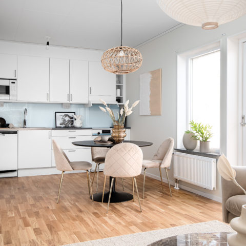 Ett vitt kök där det står ett köksbord och stolar framför