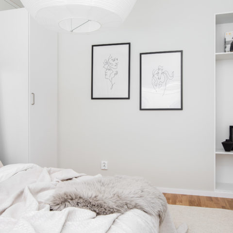 ett vitt sovrum med två tavlor på väggen