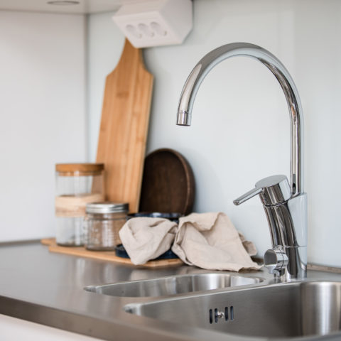 en köksbänk i rostfritt stål som det står en skärbräda och lite skålar på.