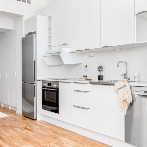 Ett ljust och modernt kök med en kromad kyl och frys.