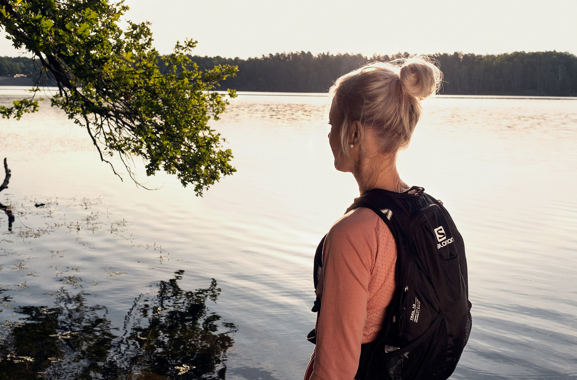 En ljushårig tjej står framför en sjö