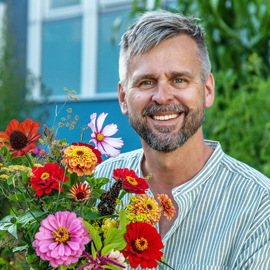 En man i randig skjorta sitter med en blombukett i famnen