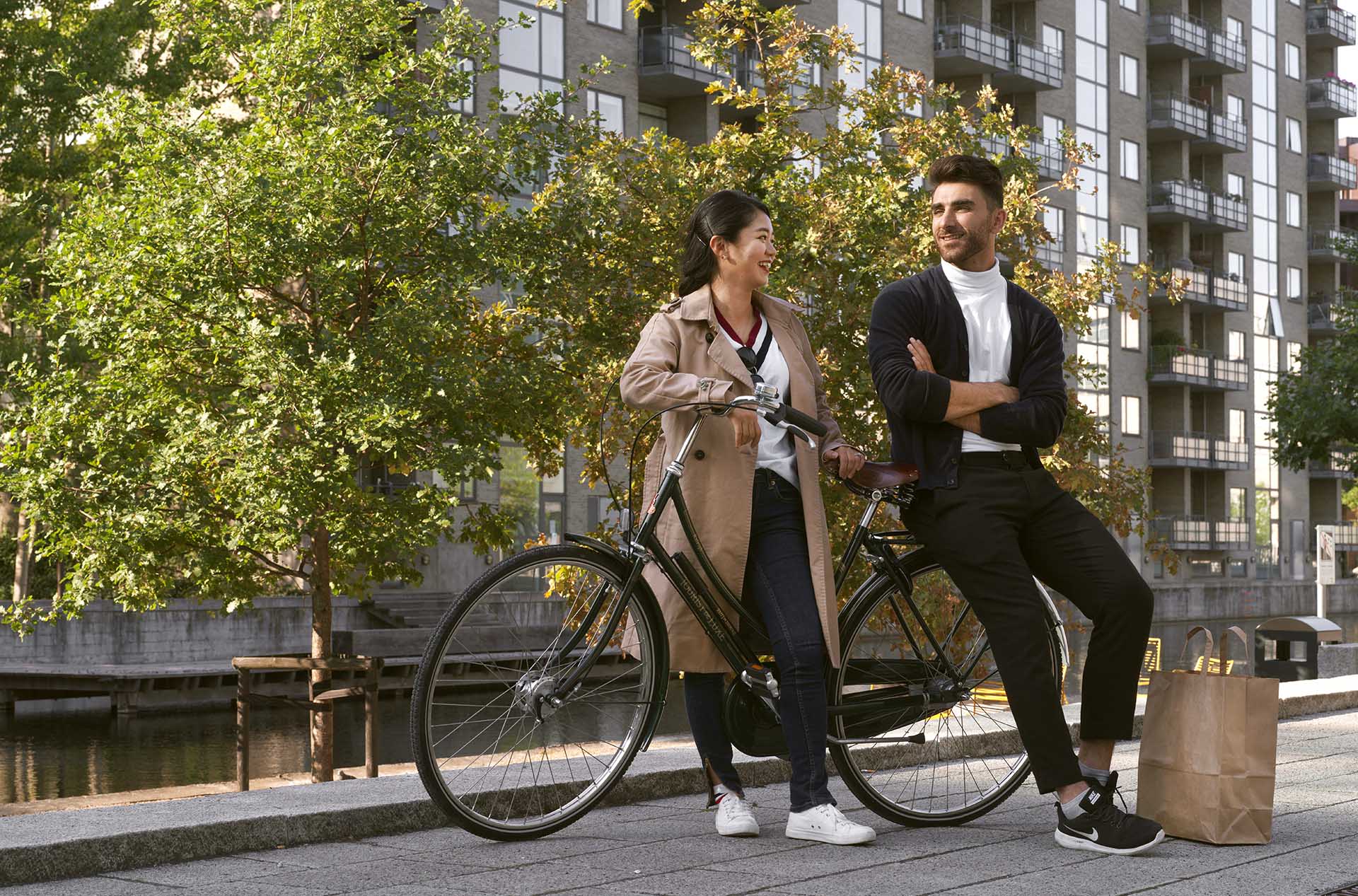 En kille och en tjej står lutade mot en cykel utomhus