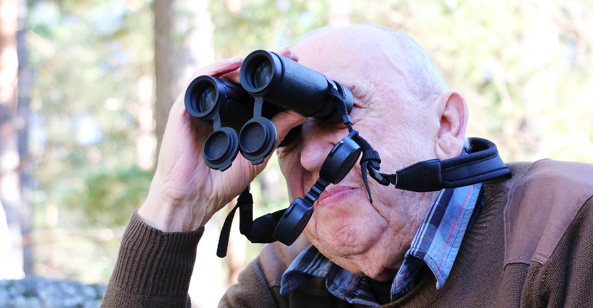 En äldre man tittar i en kikare
