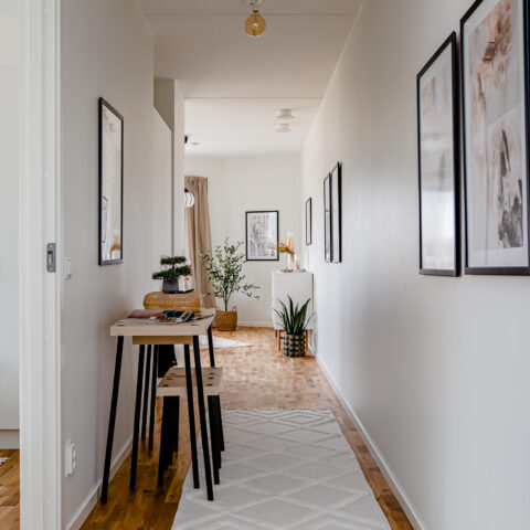 En gång i en lägenhet med satsbord och två tavlor på väggen