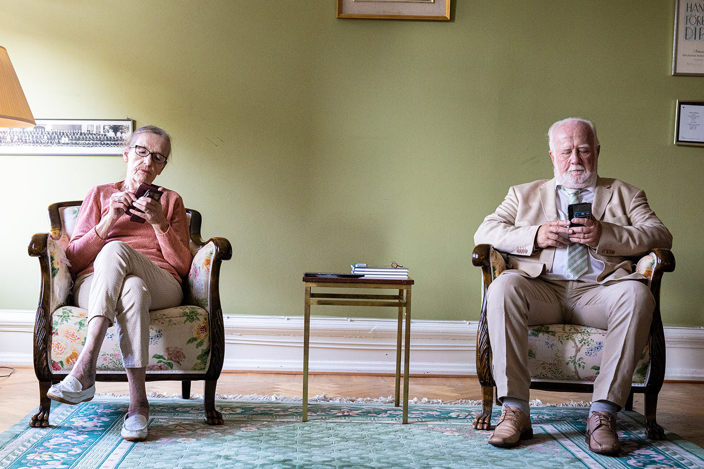 Par sitter med sina mobiler i vardagsrummet