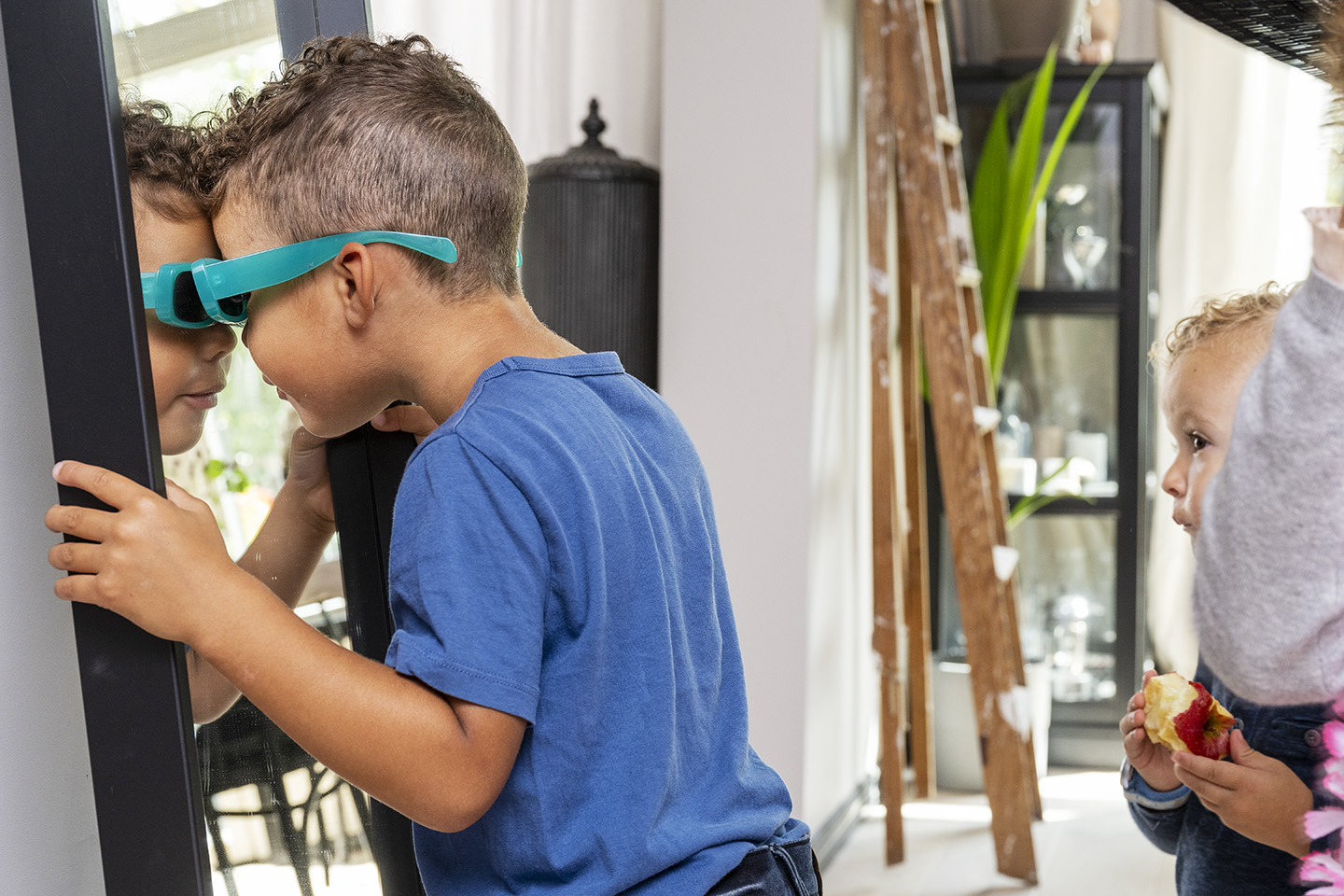Ett barn tittar in i en spegel med sina blå glasögon