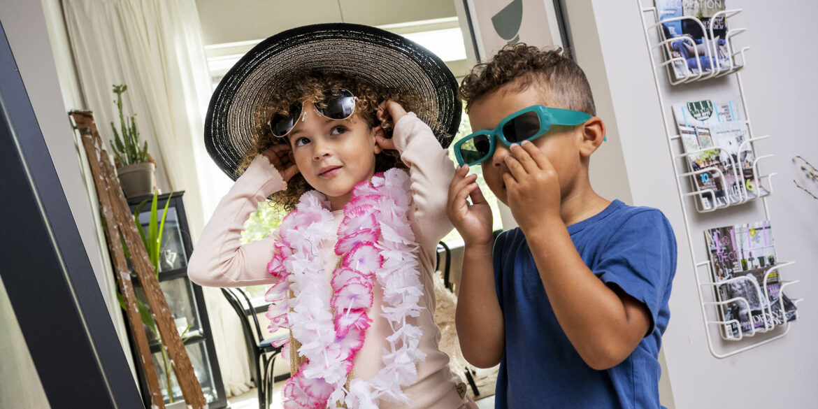 Två barn klär ut sig i roliga maskeradkläder som glasögon, hattar och boa.