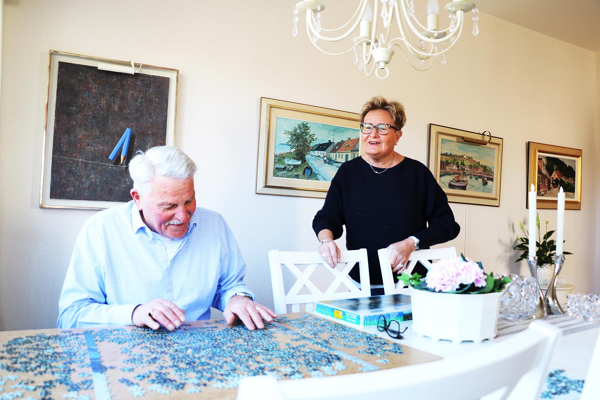 Ett äldre par lägget pussel på sitt matbord