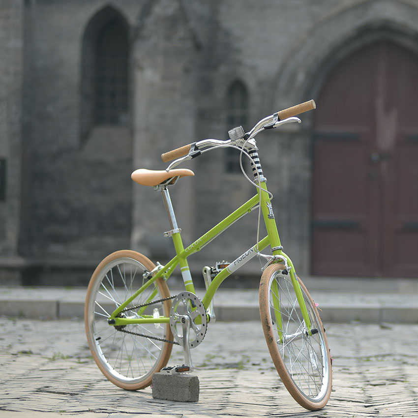 En limegrön cykel som står på en kullertensgata