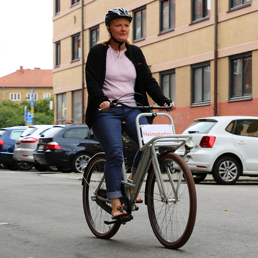 En kvinna i cykelhjälm cyklar på gatan i jeans och flipflop