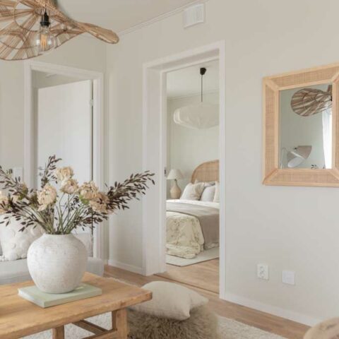 Ett soffbord i rotting som det står en vit oval vas på med blommor i