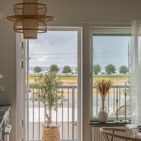 Vy från ett vardagsrum där man ser en balkongdörr som är öppen