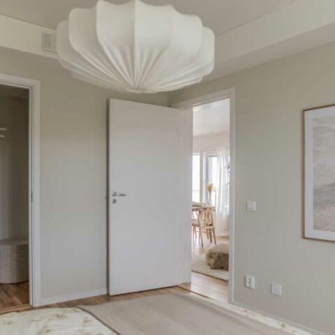 Ett ljusgrått sovrum med en stor vit lampa i taket