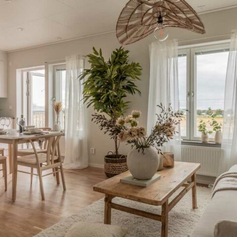 Ett vitt vardagsrum där man ser ett soffbord i trä och en köksmöbel mitt i rummet