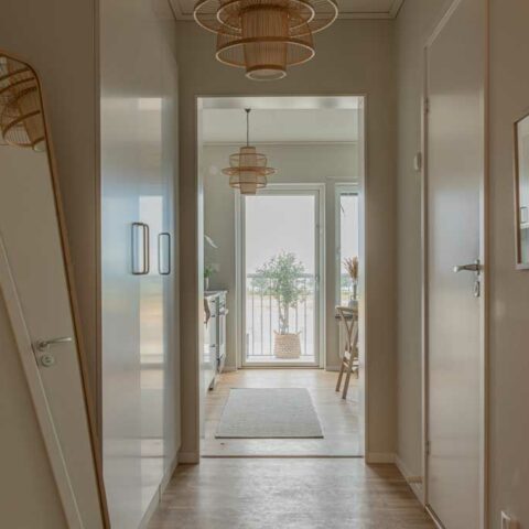 En långsmal hall där man ser dörrar på vardera sida och en spegel som lutar mot väggen