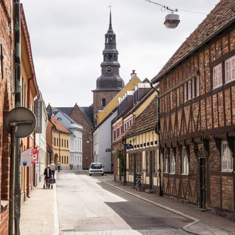 En stadsgata med hus längs sidorna och en kyrka längre bort.