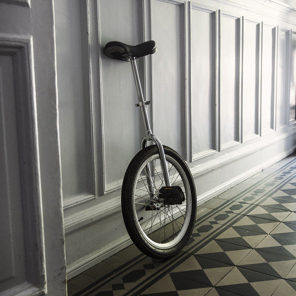 En enhjuling som står i ett trapphus som har svartvitt klinkersgolv
