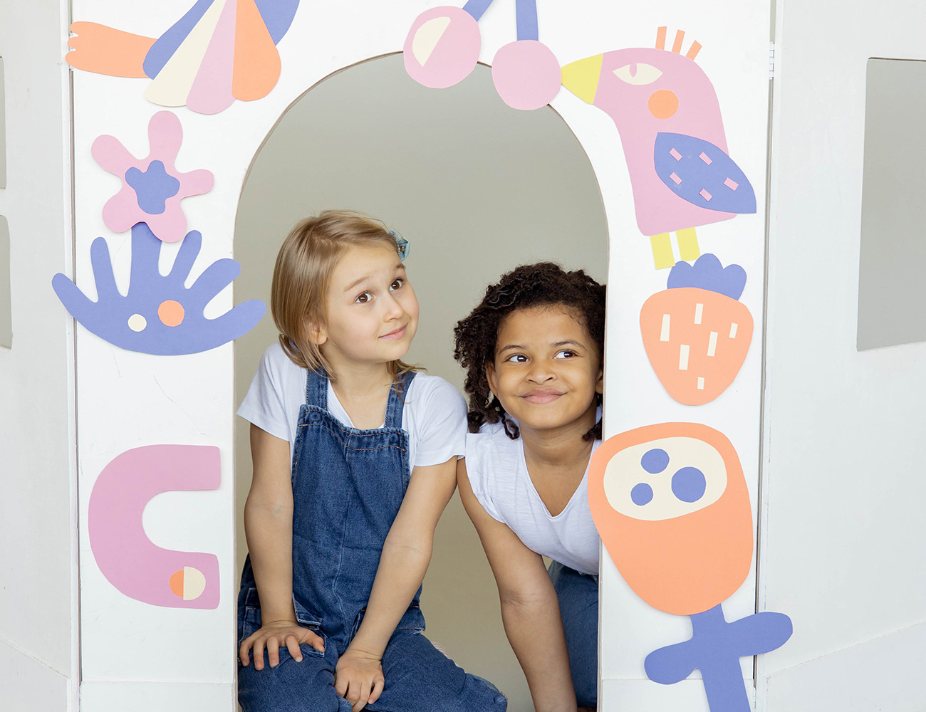 Två flickor som sitter på golvet med en målad tavla framför sig