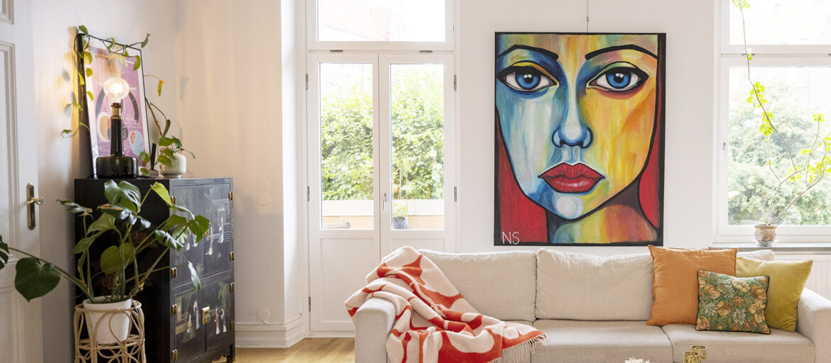 En ljus lägenhet med en färgstark tavla med ett motiv av ett kvinnoansikte