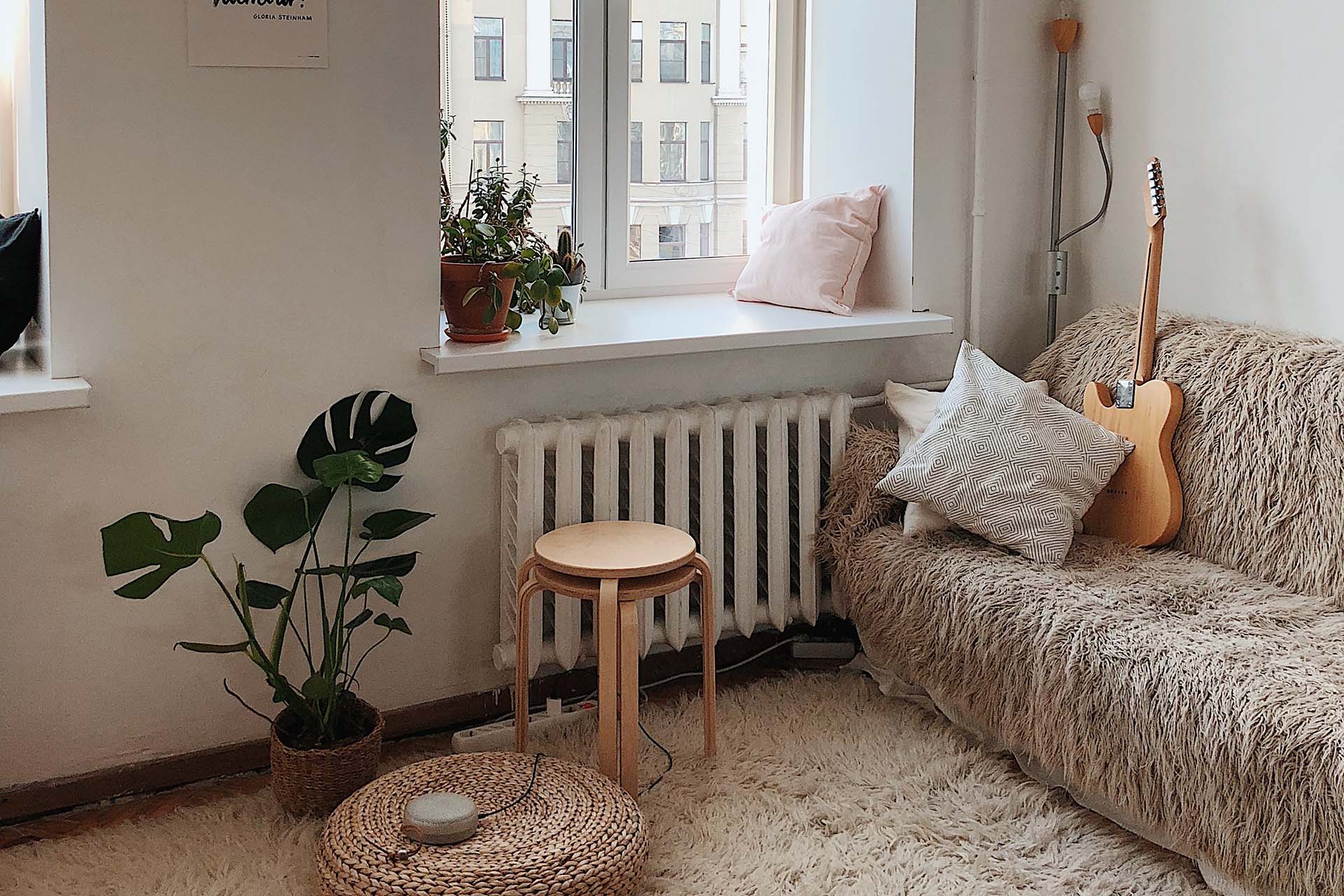 Ett ljust vardagsrum där man ser en soffa med en gitarr i och sen olika inredningsdetaljer i beige