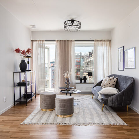 Vardagsrum med soffahörna och stort fönsterparti.