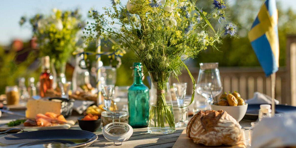 Ett dukat bord med porslin, blomvaser med stora gröna blommor i och en grön glasflaska