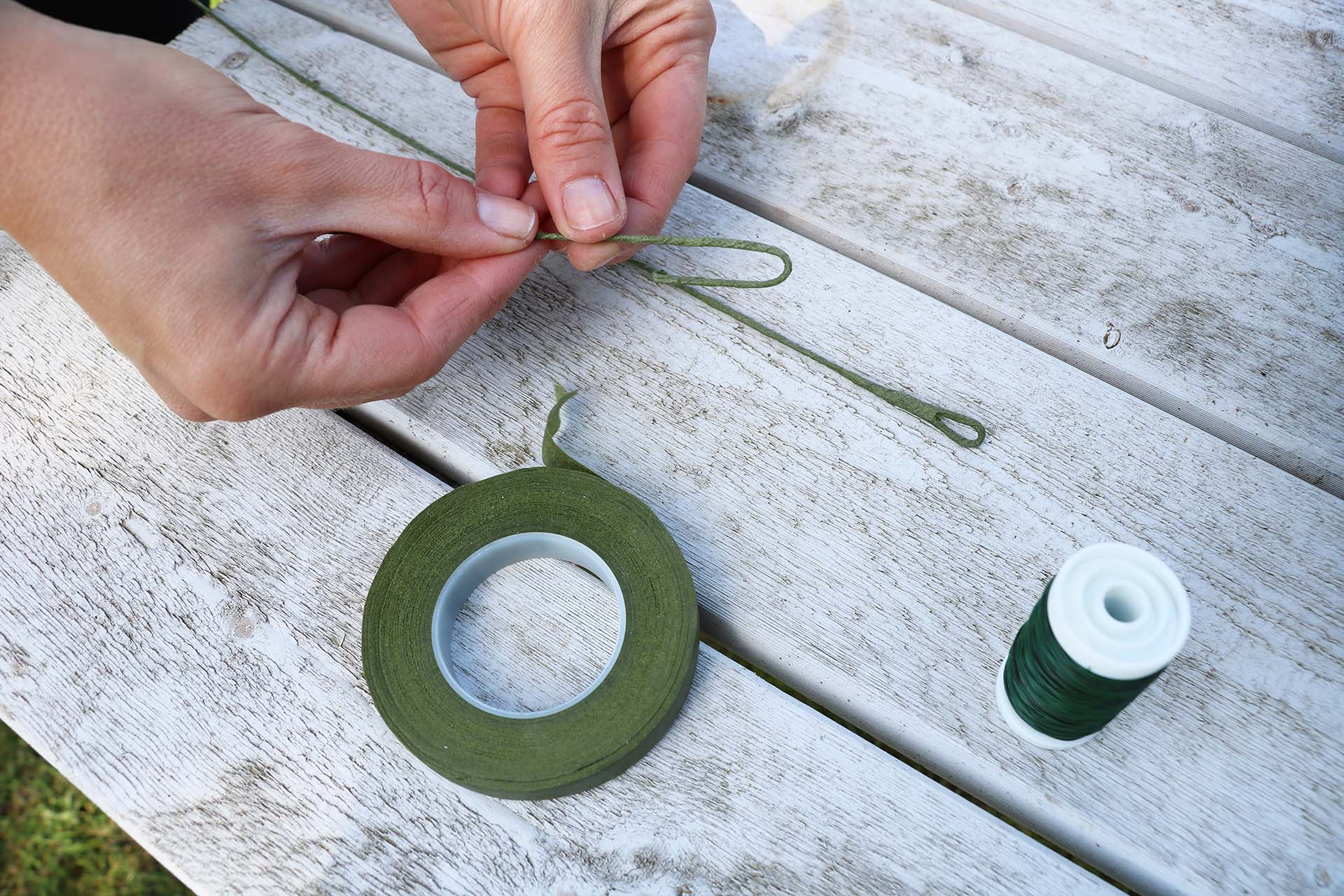 En grön ståltråd som någon binder en knut i