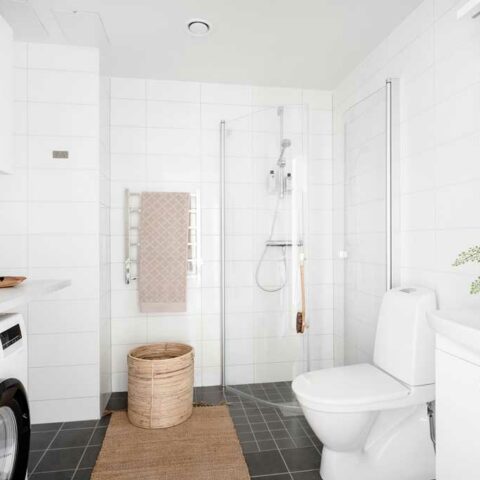 Ett vitt badrum med en rottingmatta och rotting tvättkorg