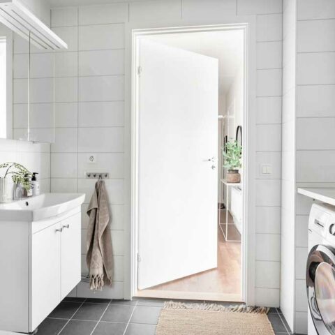 Ett badrum med vitt kakel och grå klinkers