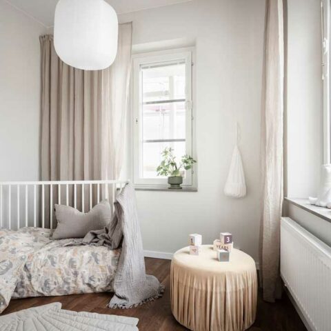 Ett barnrum med vita och beige textilier.
