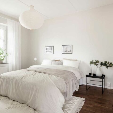 Ett vitt sovrum med en stor säng med vita textilier