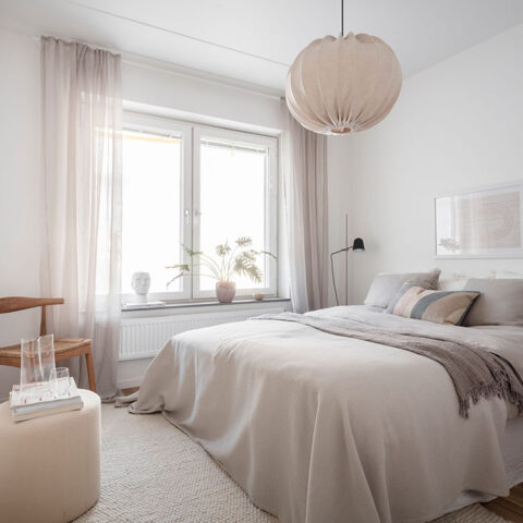 Ett inrett sovrum med dubbelsäng, fåtölj och ett litet bord.